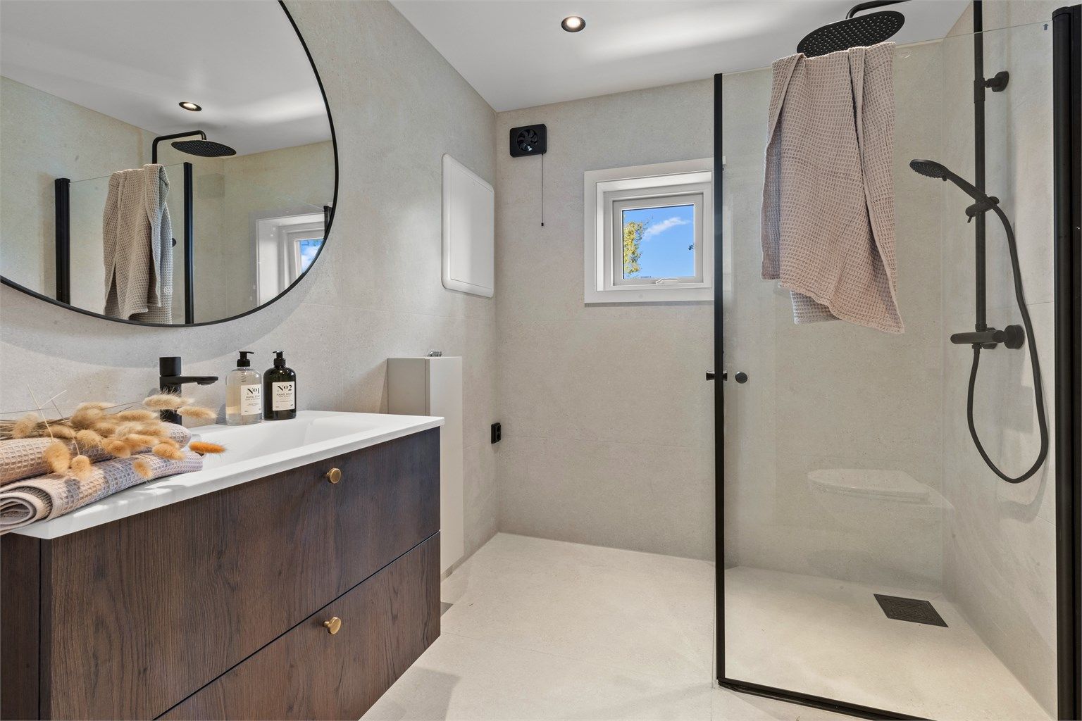 Flislagt bad med flotte detaljer i mørkt tre og svart. 