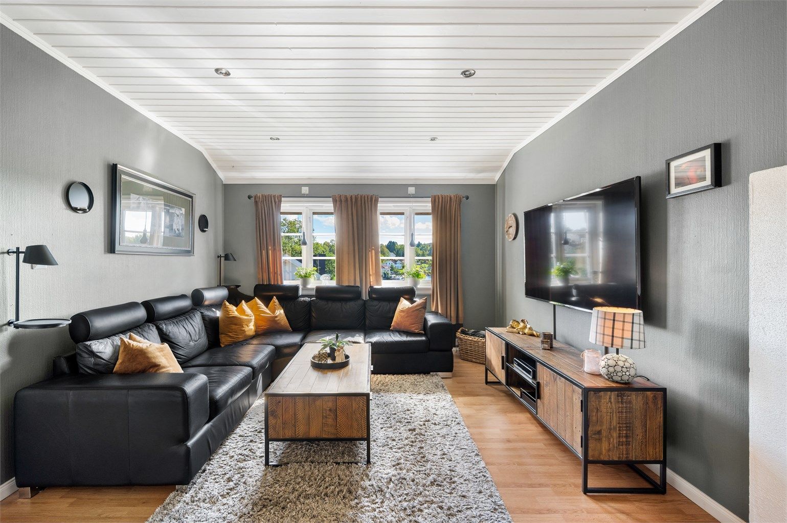 Loftstuen er innredet som en romslig TV-stue med downlights i taket og vinduer mot elva.