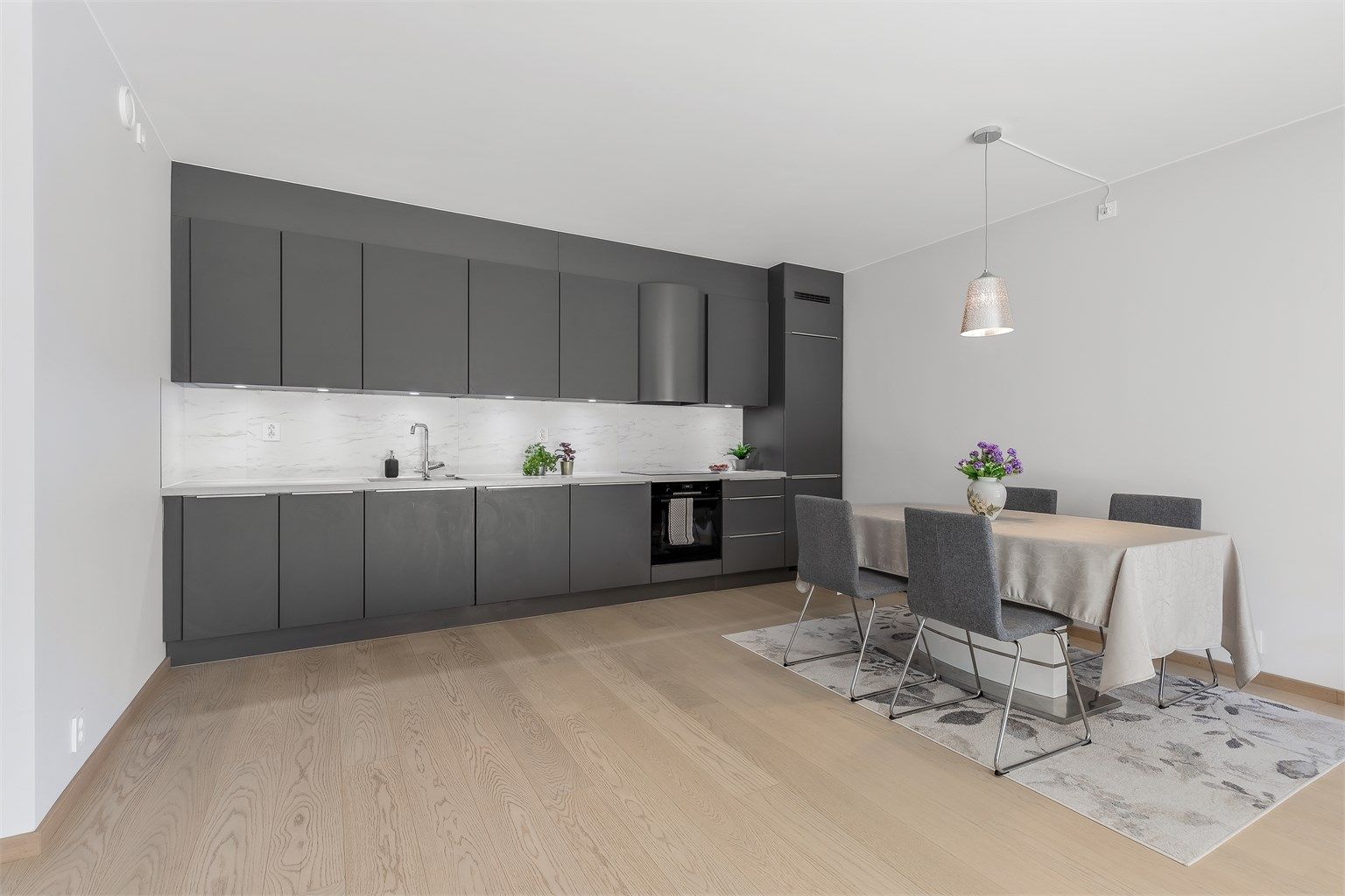 Åpen kjøkkenløsning. Innredning fra byggeår. Glatte fronter. Benkeplate med laminert overflate. Kjøkkenvask med armatur. Integrert stekeovn, platetopp, oppvaskmaskin og kjøleskap med fryser.