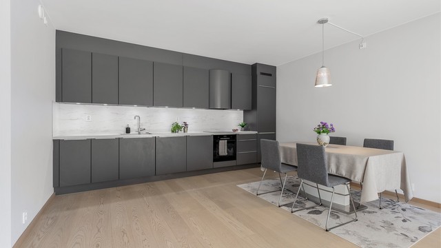 Åpen kjøkkenløsning. Innredning fra byggeår. Glatte fronter. Benkeplate med laminert overflate. Kjøkkenvask med armatur. Integrert stekeovn, platetopp, oppvaskmaskin og kjøleskap med fryser.