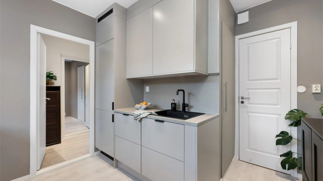 Integrert kjøleskap med fryser i hjørnet. Til høyre er dør til bod.