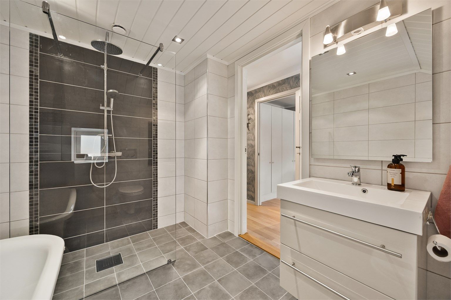 Rommet har vegghengt toalett, downlights i taket og en moderne servantinnredning.