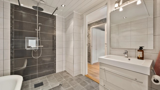Rommet har vegghengt toalett, downlights i taket og en moderne servantinnredning.