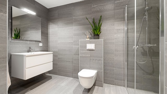 Badet er utstyrt med vegghengt toalett og dusj med innfellbare glassdører