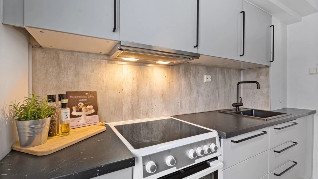 Kjøkkeninnredning fra IKEA med god skap- og benkeplass med lun farge og stilige sorte detaljer
