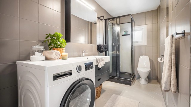 Badet har dusjkabinett, gulvstående toalett og opplegg for vaskemaskin.