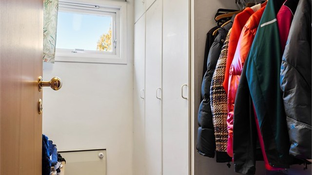 Walk-in garderoben har plassbygget skapinnredning i hvit og glatt utførelse.