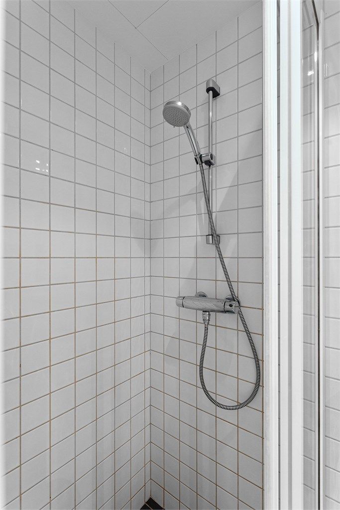 Dusjhjørne med skyvbare glassdører og flislagte overflater.