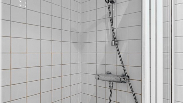 Dusjhjørne med skyvbare glassdører og flislagte overflater.