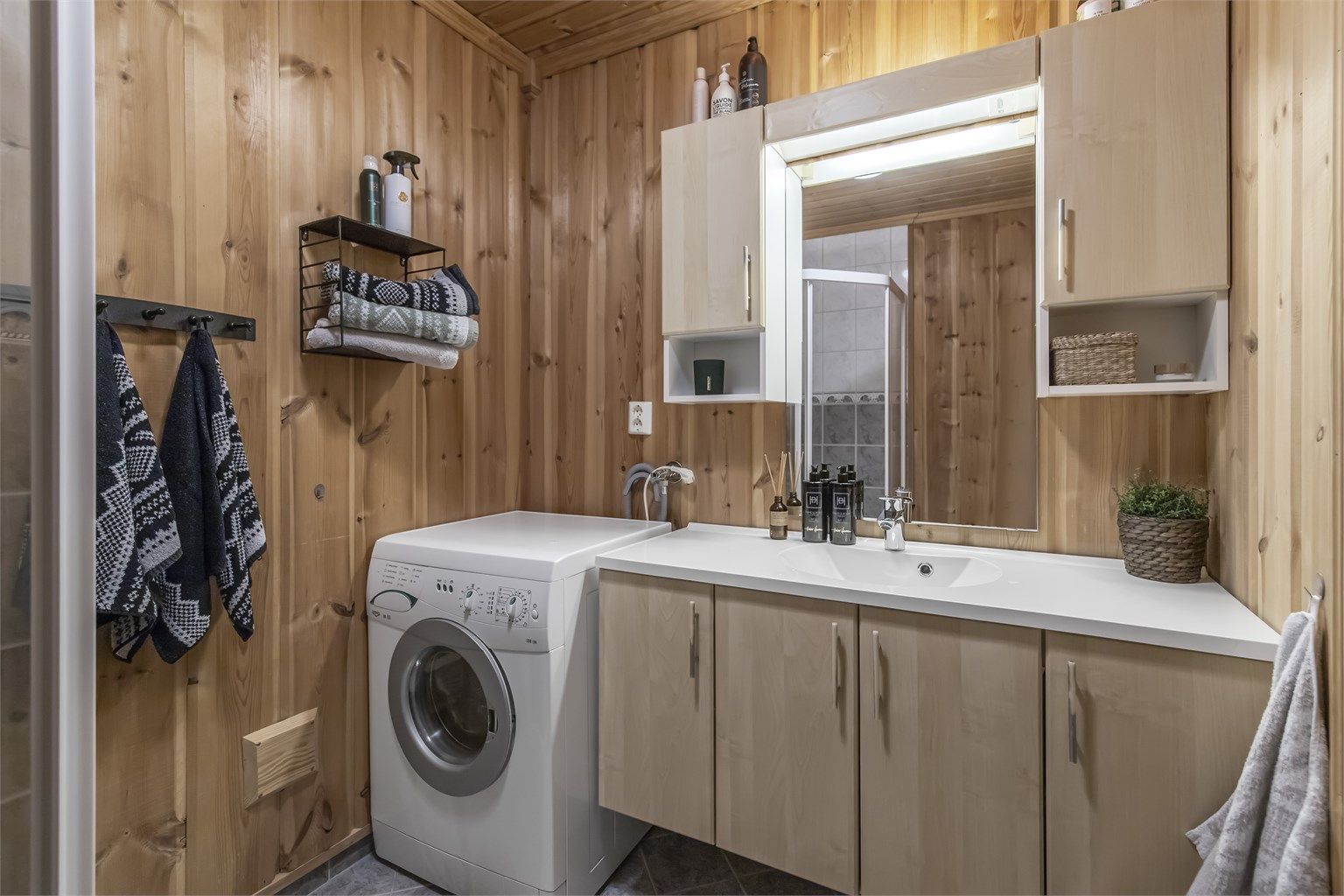 Bad i hovedetasjen er innredet med dusjhjørne, servant i innredning, toalett og opplegg til vaskemaskin