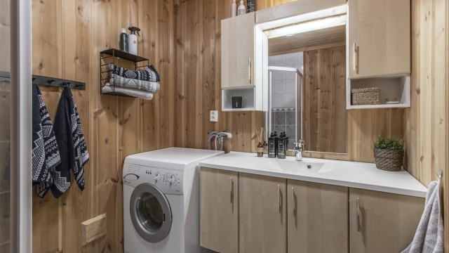 Bad i hovedetasjen er innredet med dusjhjørne, servant i innredning, toalett og opplegg til vaskemaskin