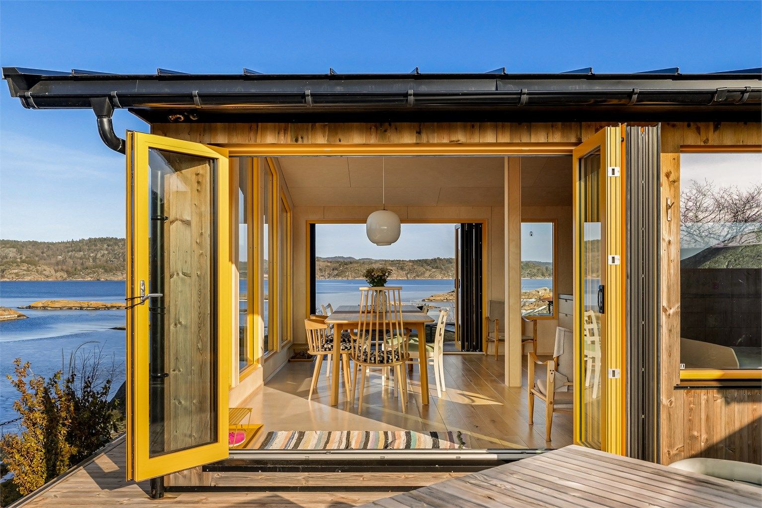 Luftig: Åpnes foldedørveggene på hver side av stuen blir terrassen en naturlig fortsettelse av dette lyse luftige rommet. Møbleringen er lett og fleksibel. Legg også merke til at innvendig gangarealet mellom terrassene er av betong. 