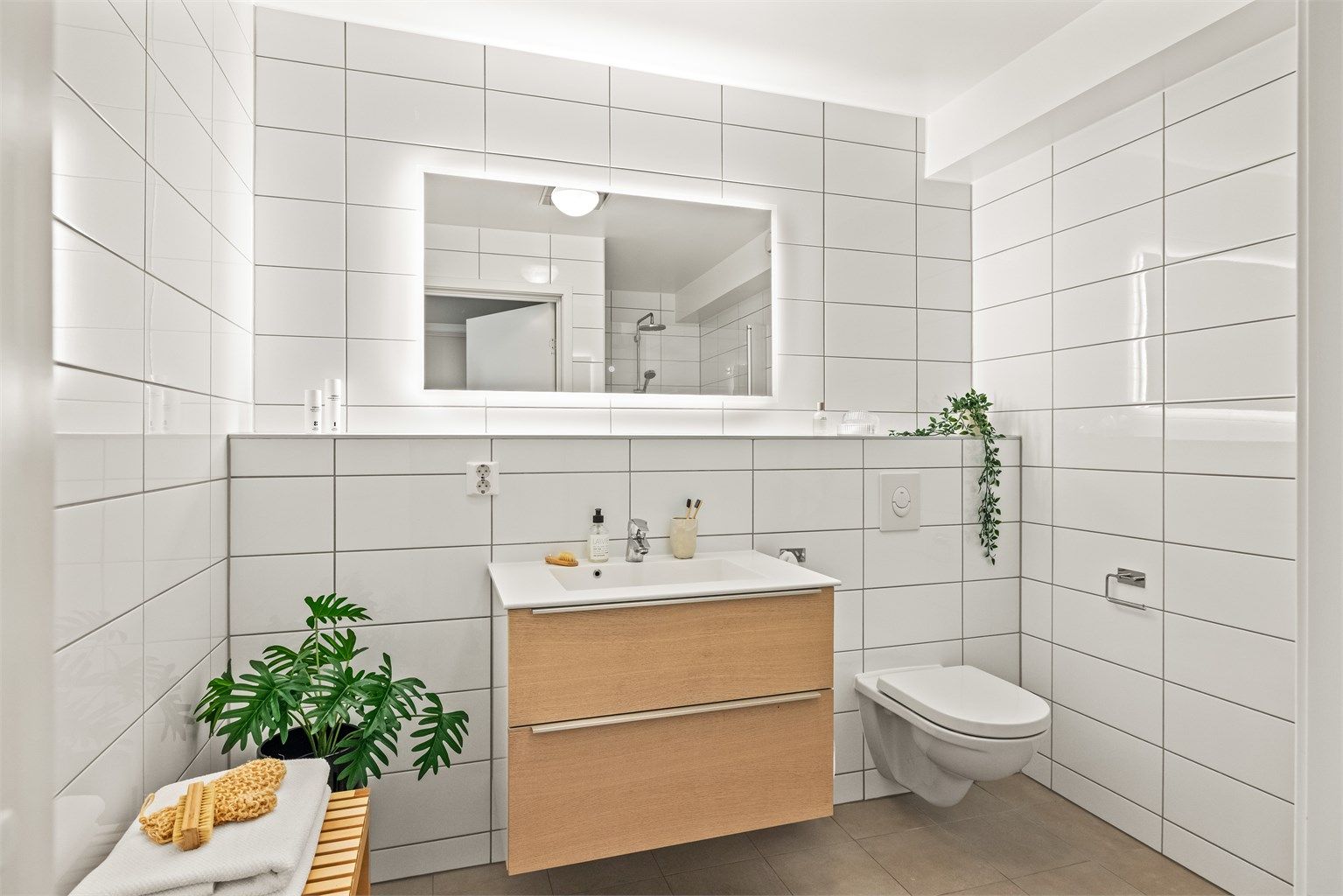 Badet i underetasjen er flislagt og har servantseksjon med skuffer og speil med integrert belysning.