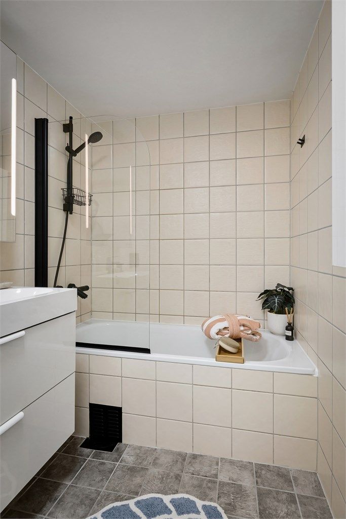  Badet er innredet med vegghengt klosett, servant med innredning, speil med lys og badekar med svingbar glassdør