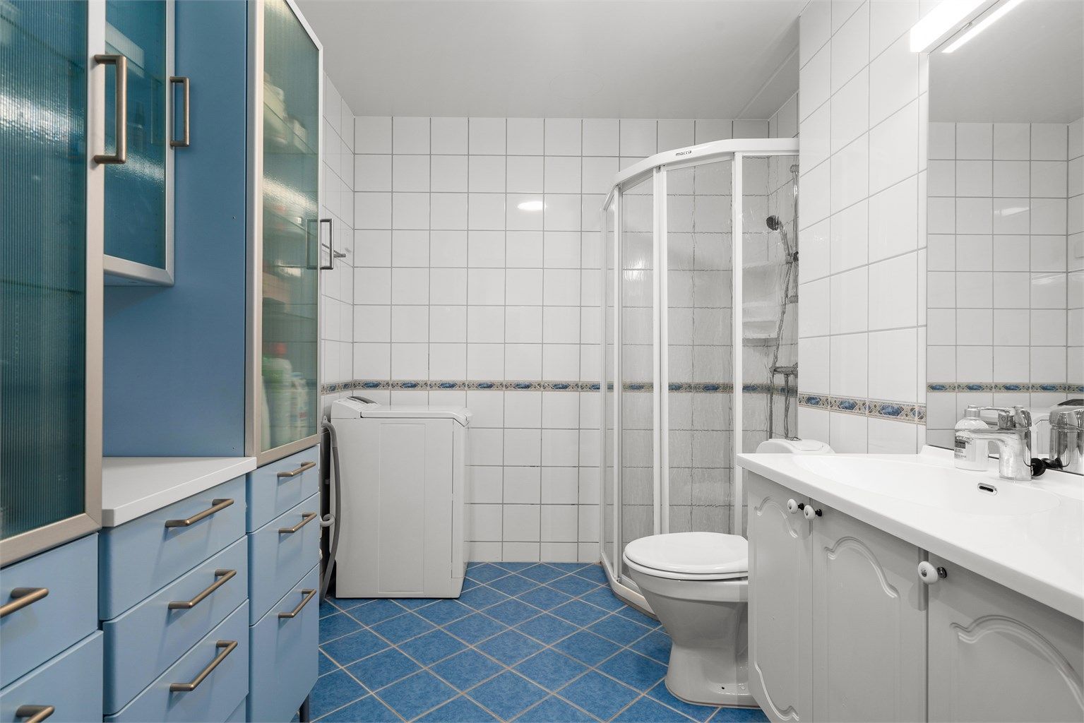 Badet har flislagte overflater med elektrisk gulvvarme, dusjnisje med glassdører og opplegg for vaskemaskin.