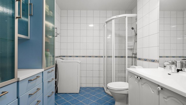 Badet har flislagte overflater med elektrisk gulvvarme, dusjnisje med glassdører og opplegg for vaskemaskin.
