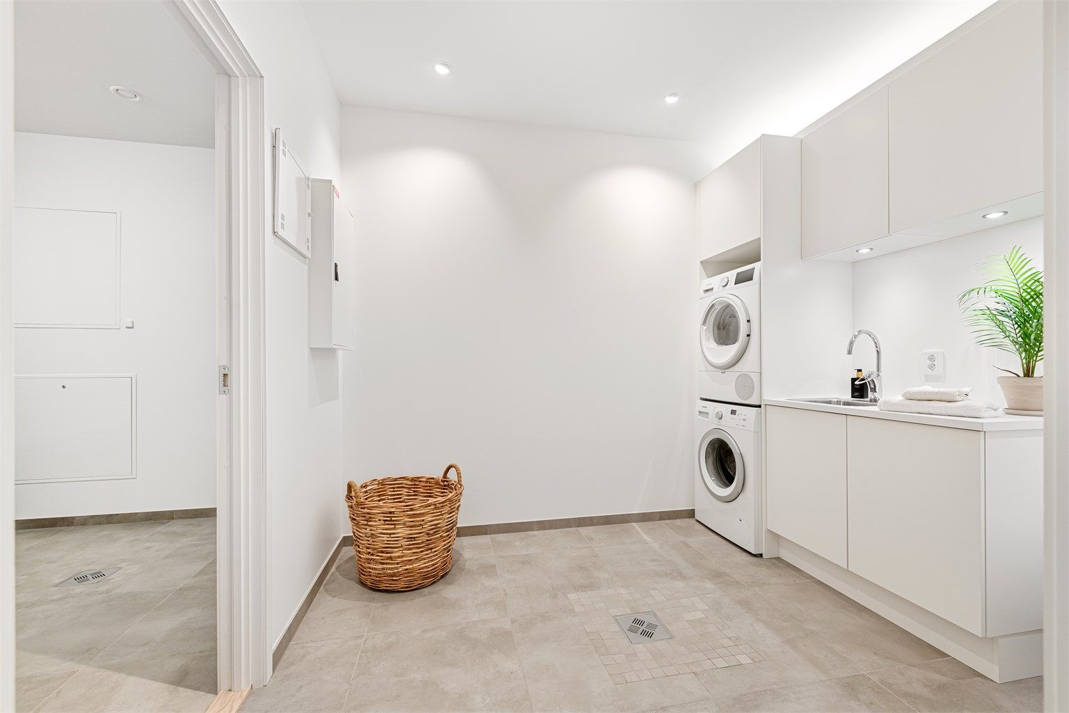 Vaskerom med romslig innredning fra HTH med hvite glatte fronter og god oppbevaringsplass. Benkeplate av laminat med nedfelt skyllekum med ett-greps armatur. Opplegg for vaskemaskin og tørketrommel.