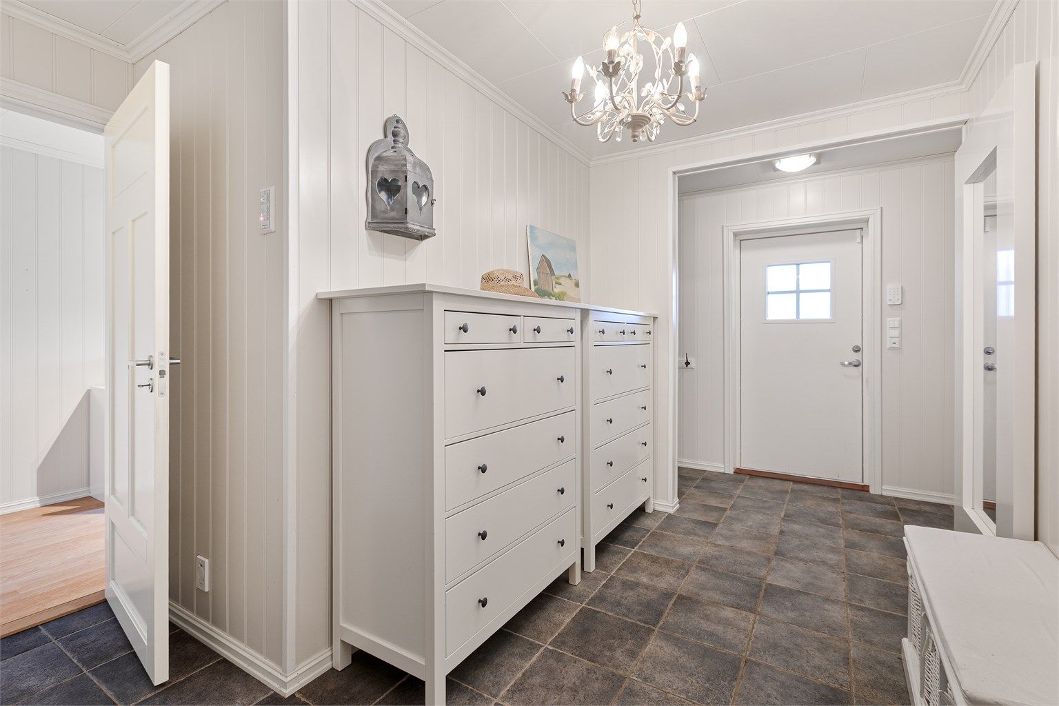 Velkommen inn i en lys entré med flislagt gulv. Her er det varmekabler som gir en behagelig start på dagen.