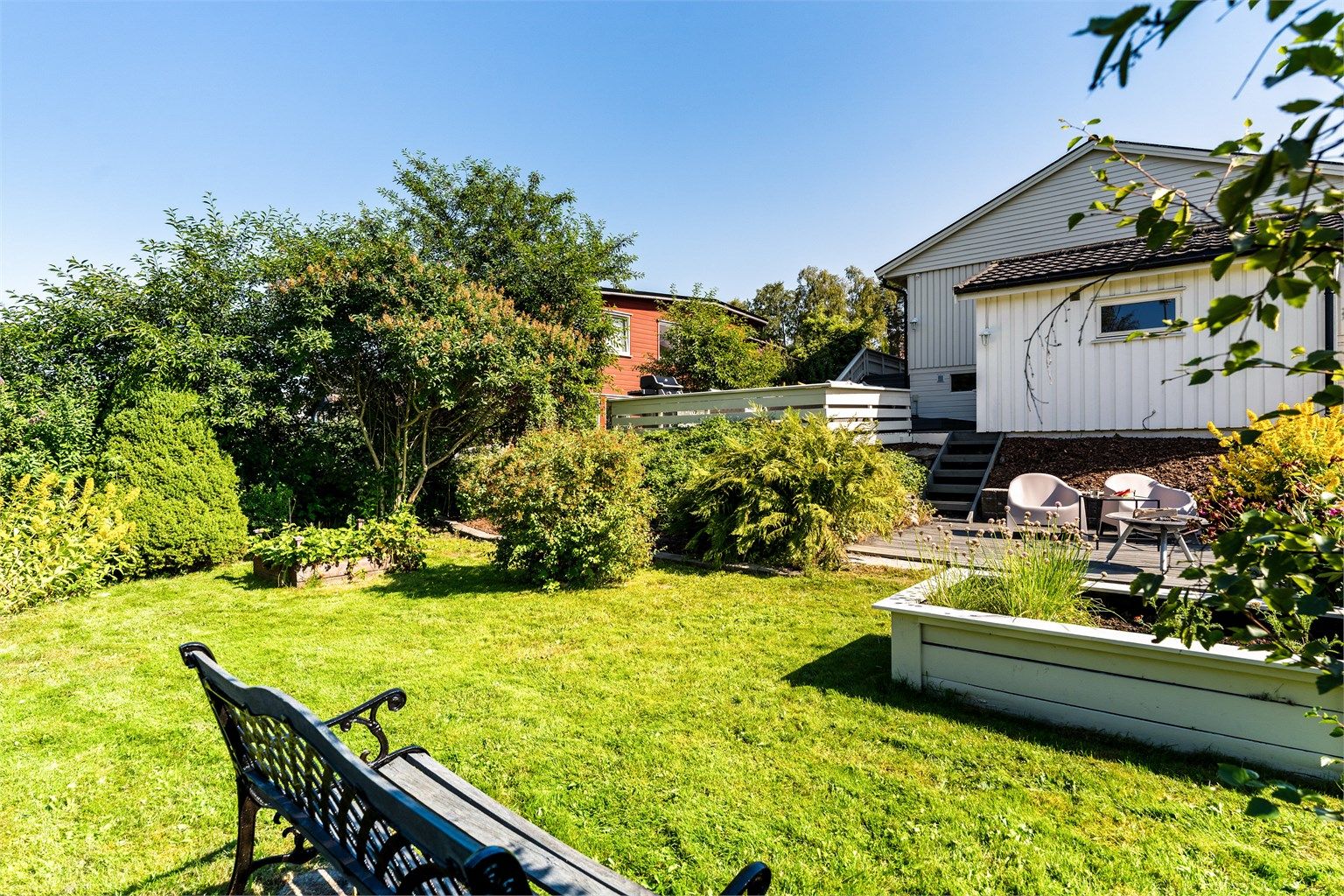 Herlig hage med lite innsyn pent opparbeidet med grus, belegningsstein, diverse beplantninger, bærbusker, terrasse på terreng og sittegrupper. 