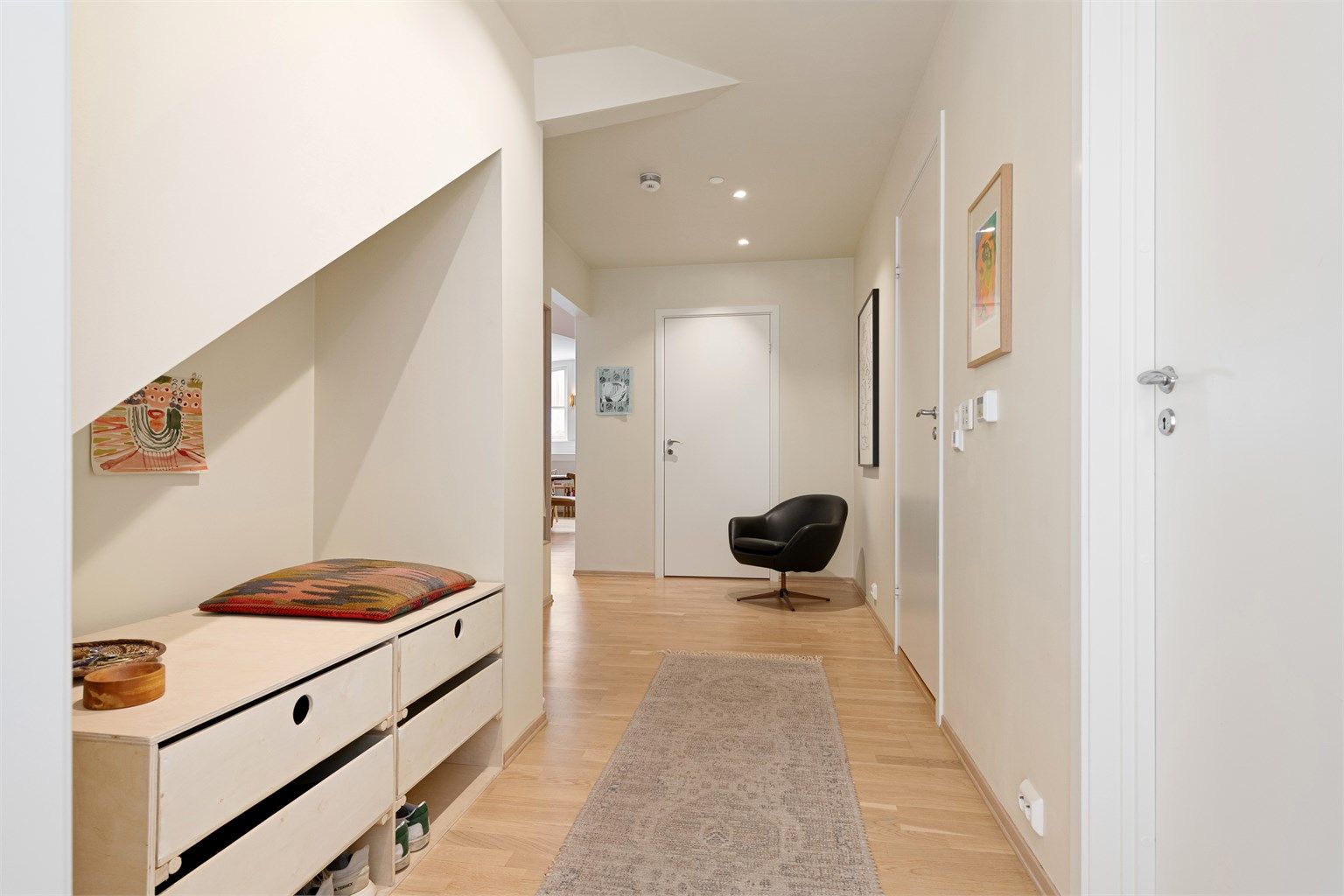 Lys og innbydende entré med parkett på gulvet og downlights i taket.