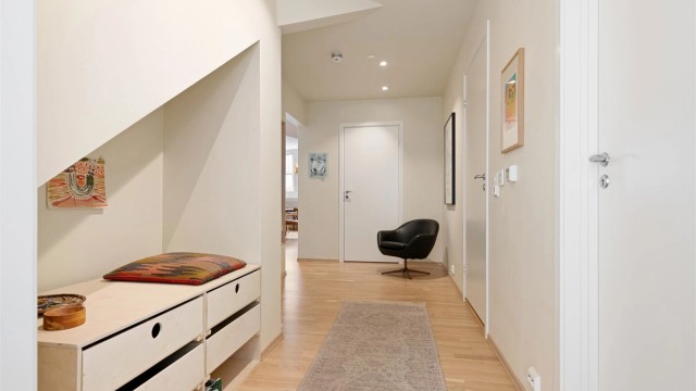 Lys og innbydende entré med parkett på gulvet og downlights i taket.