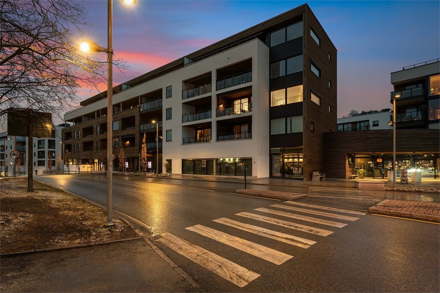 Bygget fra 2022 har en moderne fasade med en kombinasjon av trekledning og pussede fasadeplater.