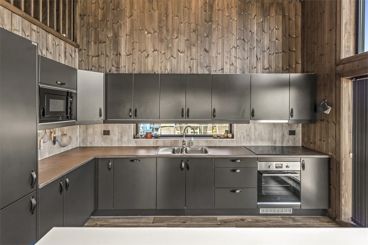 Den åpne kjøkken- og stueløsningen er hyttens hjerte, med vindusflater fra gulv til tak som gir panoramautsikt uansett hvor du oppholder deg i rommet. 