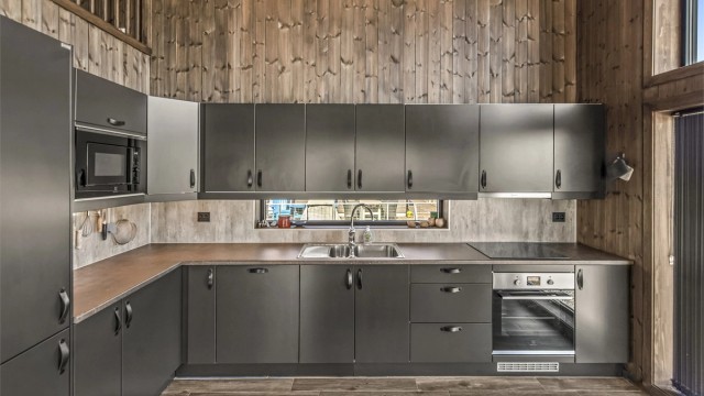 Den åpne kjøkken- og stueløsningen er hyttens hjerte, med vindusflater fra gulv til tak som gir panoramautsikt uansett hvor du oppholder deg i rommet.