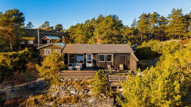 HYTTA ER SVART på utsiden og ligger lavt i landskapet.