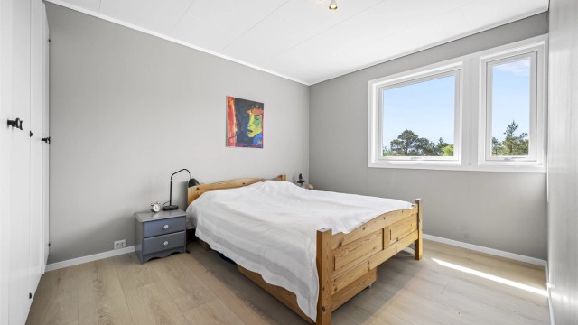 Ett av to soverom i første etasje, med laminat på gulvet og plass til garderobeløsning.