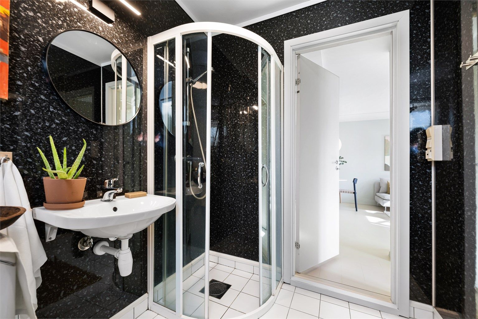Dusjhjørne med dører, vegghengt servant og gulvstående toalett. Badet har mekanisk avtrekksvifte.