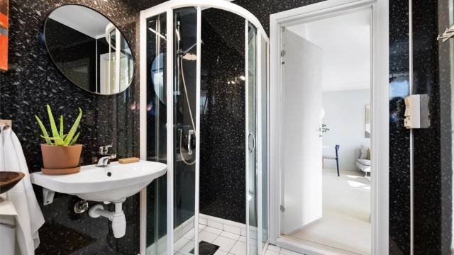 Dusjhjørne med dører, vegghengt servant og gulvstående toalett. Badet har mekanisk avtrekksvifte.