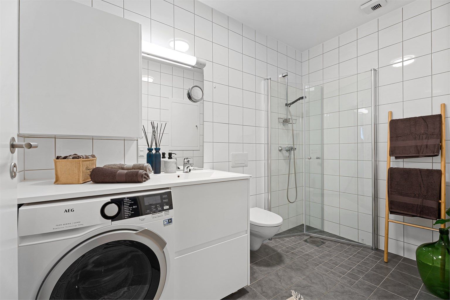 Badet er flislagt og har en større dusjnisje med innfellbare dører. 