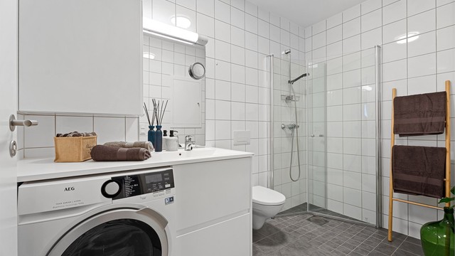 Badet er flislagt og har en større dusjnisje med innfellbare dører.