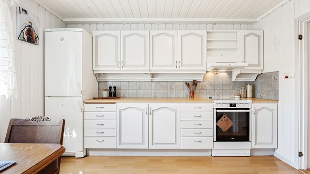 Kjøkkenet er utstyrt med laminert benkeplate, frittstående komfyr og ventilator.