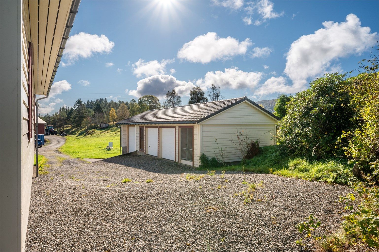 Pent opparbeidet tomt med gruslagt tun, plenareal, diverse beplantinger og garasjebygg.