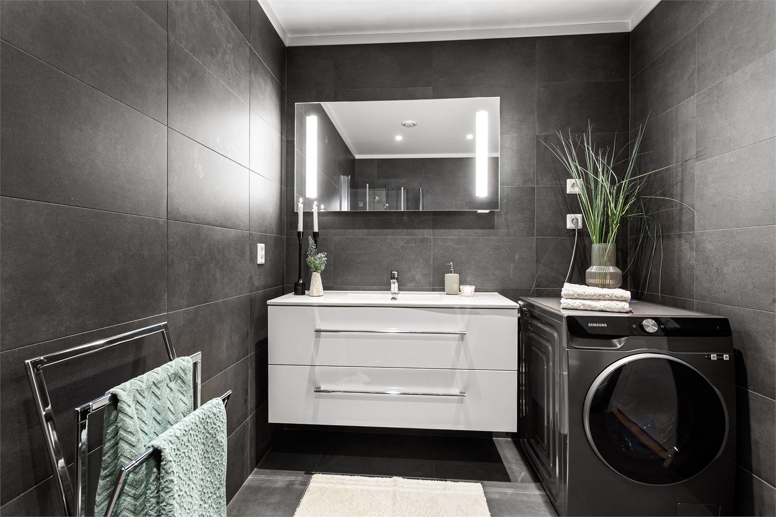 Vegghengt baderomsinnredning med ovenpåliggende servant. Speil med sidelys over servant. Opplegg for vaskemaskin.