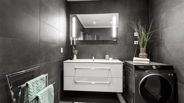 Vegghengt baderomsinnredning med ovenpåliggende servant. Speil med sidelys over servant. Opplegg for vaskemaskin.