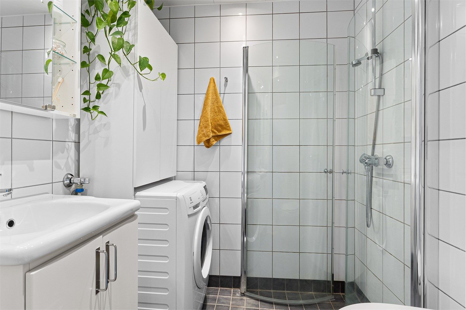 Flislagt bad med elektrisk gulvvarme, downlights i himlingen og opplegg for vaskemaskin – en komplett og velutstyrt baderomsløsning som gir god komfort året rundt.