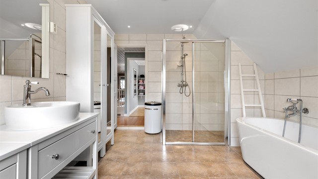 Badet i loftsetasjen har flislagt gulv og vegger, samt innfelt spottbelysning i taket.