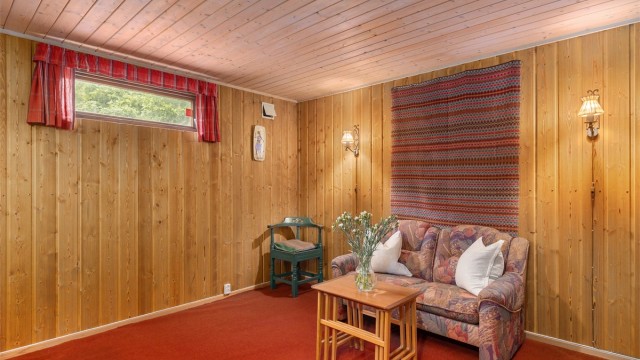 Romslig rom innredet som kjellerstue med god plass til sofagruppe, kommoder og til lagring