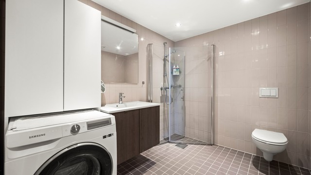 Flislagt bad fra 2022 med vannbåren gulvvarme. Badet har vegghengt toalett, dusjhjørne med glassvegger og opplegg for vaskemaskin.