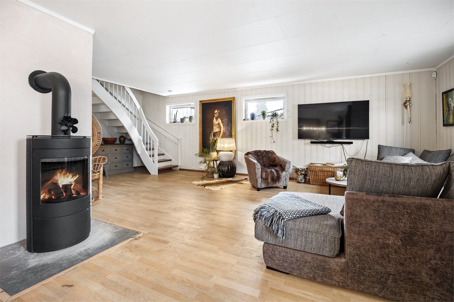 En frittstående peisovn gir både varme og hygge, supplert av en luft-til-luft varmepumpe for effektiv oppvarming.