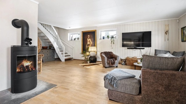 En frittstående peisovn gir både varme og hygge, supplert av en luft-til-luft varmepumpe for effektiv oppvarming.