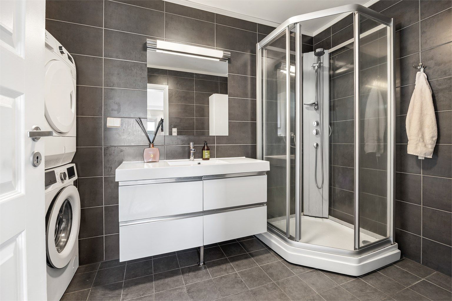 Badet har dusjkabinett og servantinnredning med oppbevaringsplass.