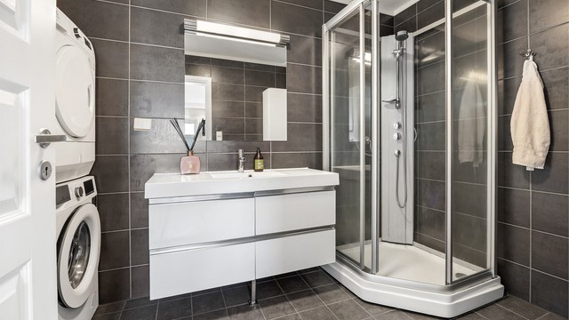 Badet har dusjkabinett og servantinnredning med oppbevaringsplass.