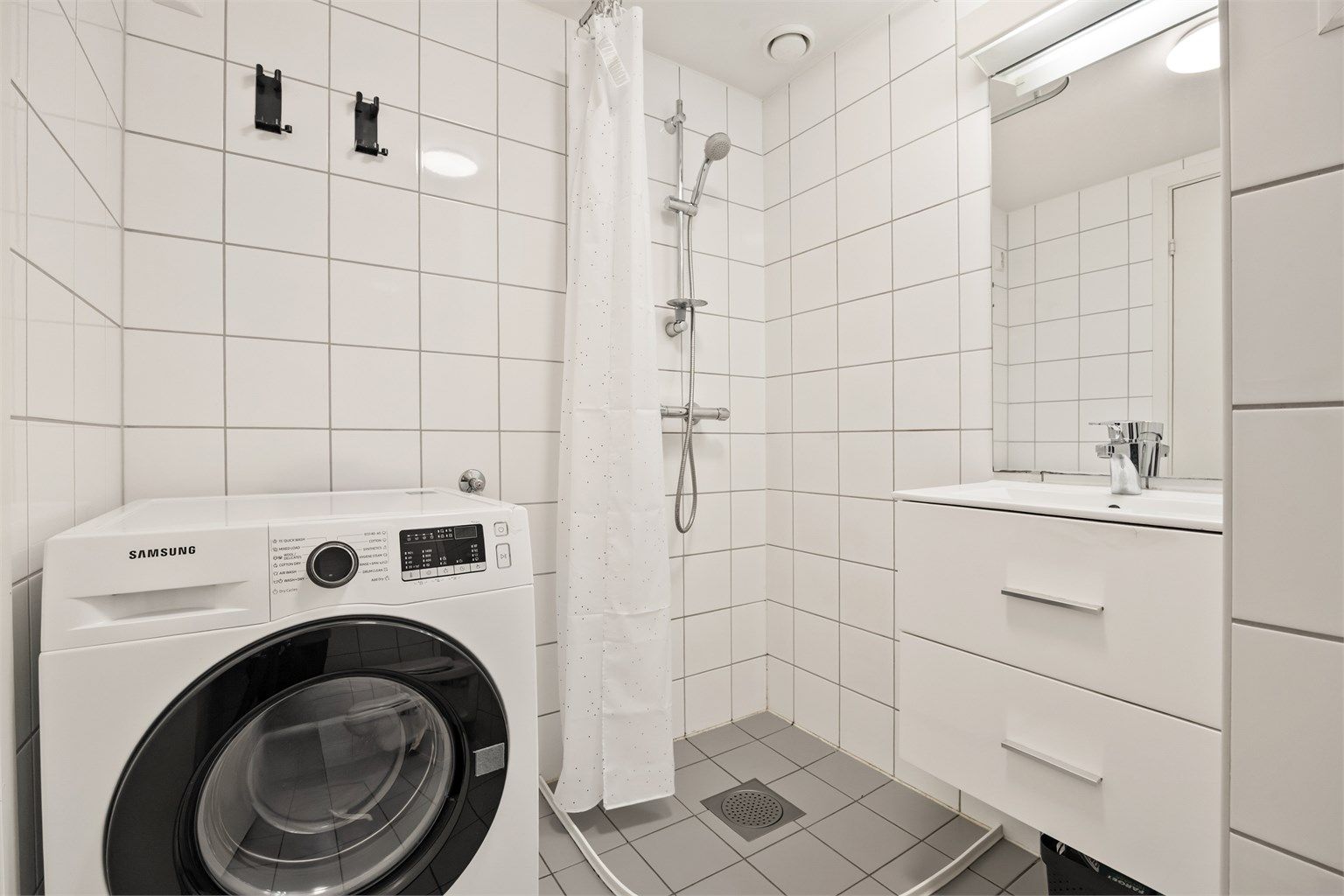 Flislagt bad med gulvvarme. Innredet med vegghengt servant og speil med overlys. Opplegg for vaskemaskin.