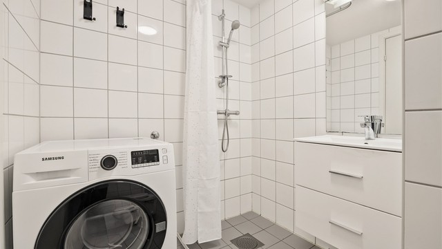 Flislagt bad med gulvvarme. Innredet med vegghengt servant og speil med overlys. Opplegg for vaskemaskin.