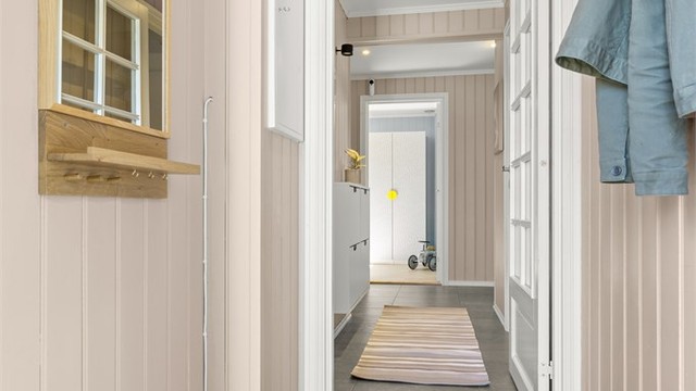 Gangen binder sammen rommene i underetasjen. En nyere glassdør slipper lyset videre inn i etasjen.