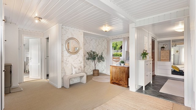 Første etasje har en romslig hall som fungerer som et ekstra oppholdsrom, med vedovn og utgang til terrasse.